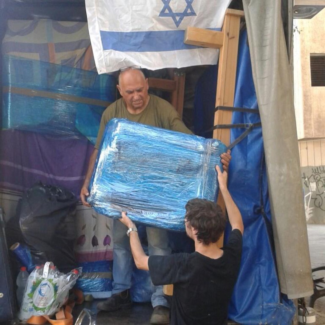 דודו והעובד מעבירים פריט עטוף מהמשאית החוצה